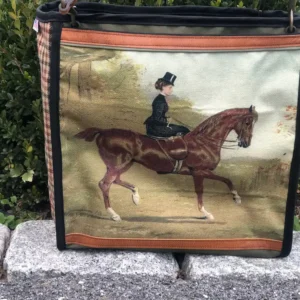 Custom black tote bag featuring a detailed illustration of a brown horse and rider, resting on a stone ledge with a leather shoulder strap.