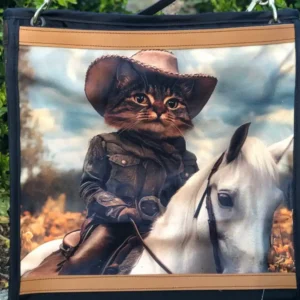 Custom black and tan tote bag featuring a detailed illustration of a cat in a cowboy hat riding a white horse, resting on a stone ledge with a leather shoulder strap.