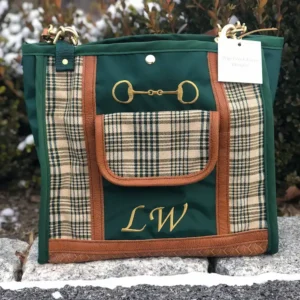 Custom green plaid tote bag, resting on a stone ledge with a leather shoulder strap.