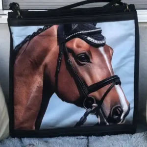 Custom black and blue tote bag featuring a detailed illustration of a horse's head, resting on a stone ledge with a leather shoulder strap.