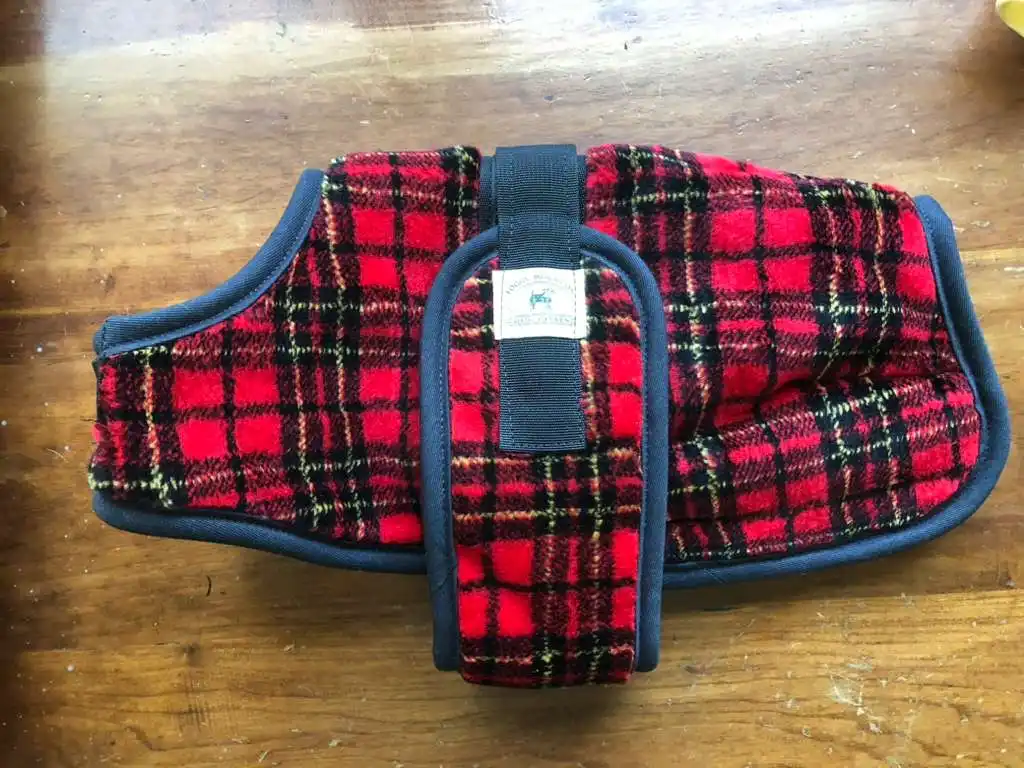 Fleece red plaid dog coat on a wooden table